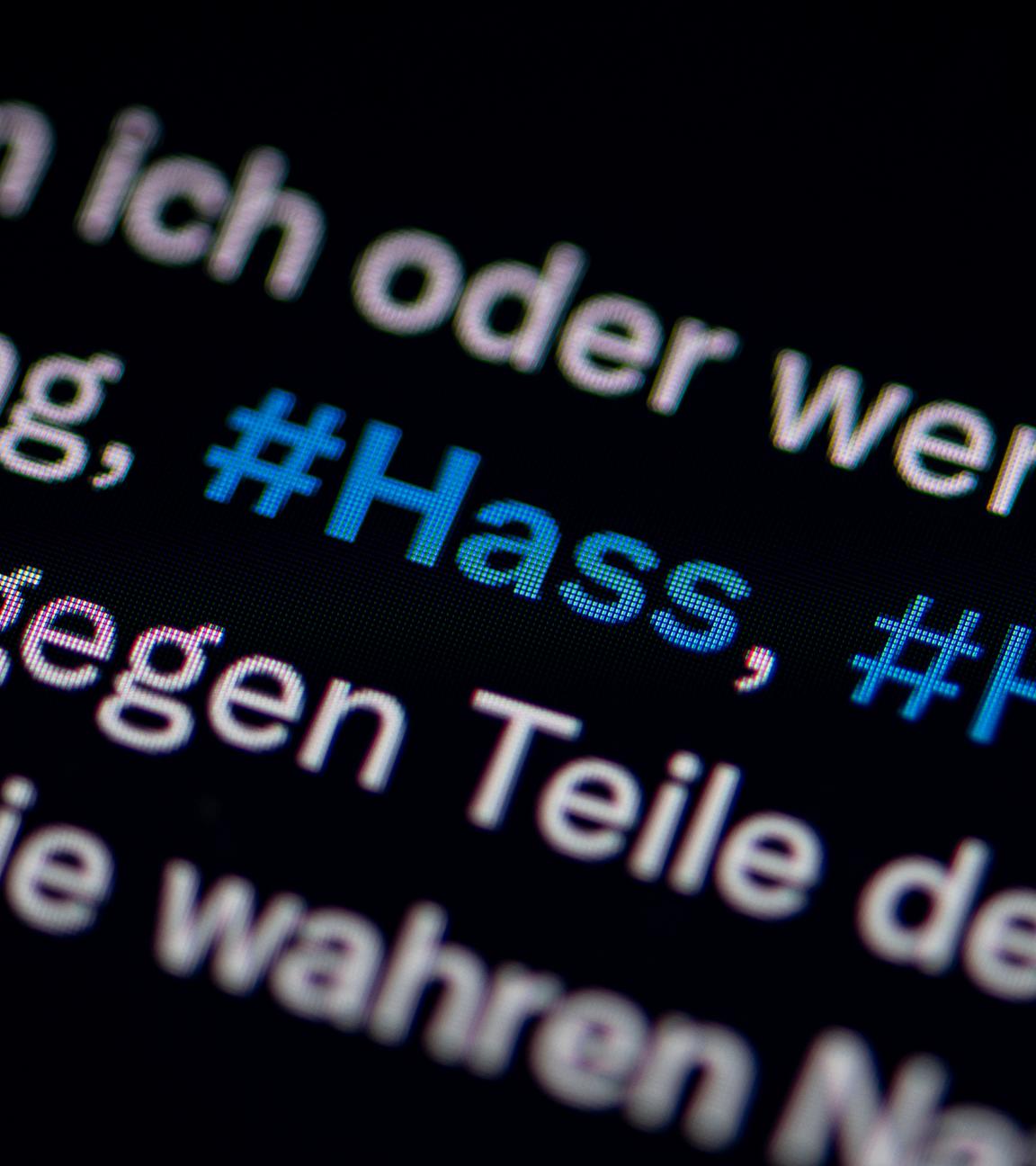 Auf dem Bildschirm eines Smartphones sieht man die Hashtags Hass und Hetze in einem Twitter-Post. 