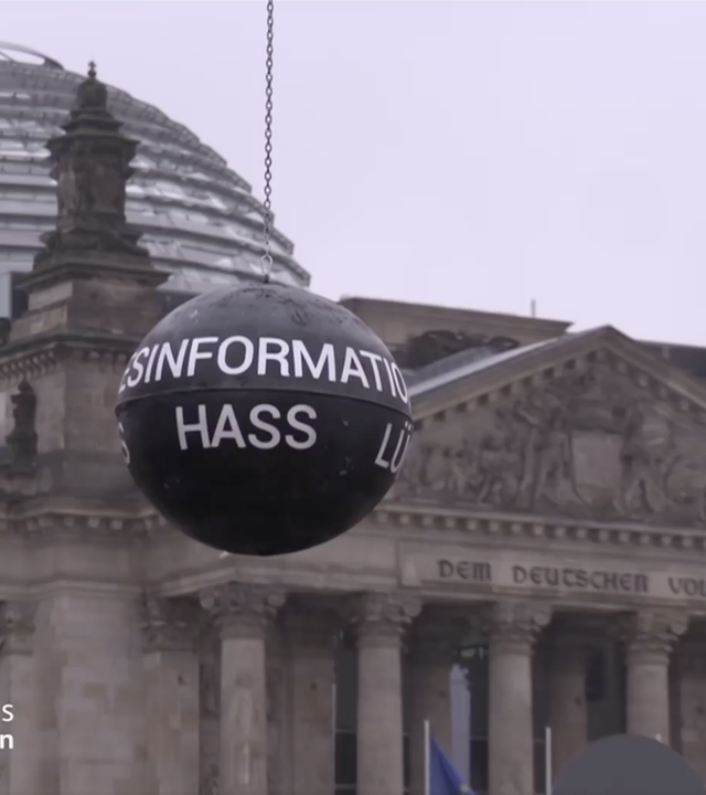Eine Abrissbirne mit Aufschriften wie "Desinformation", "Lüge" und "Hass" steht vor dem Reichstagsgebäude in Berlin.