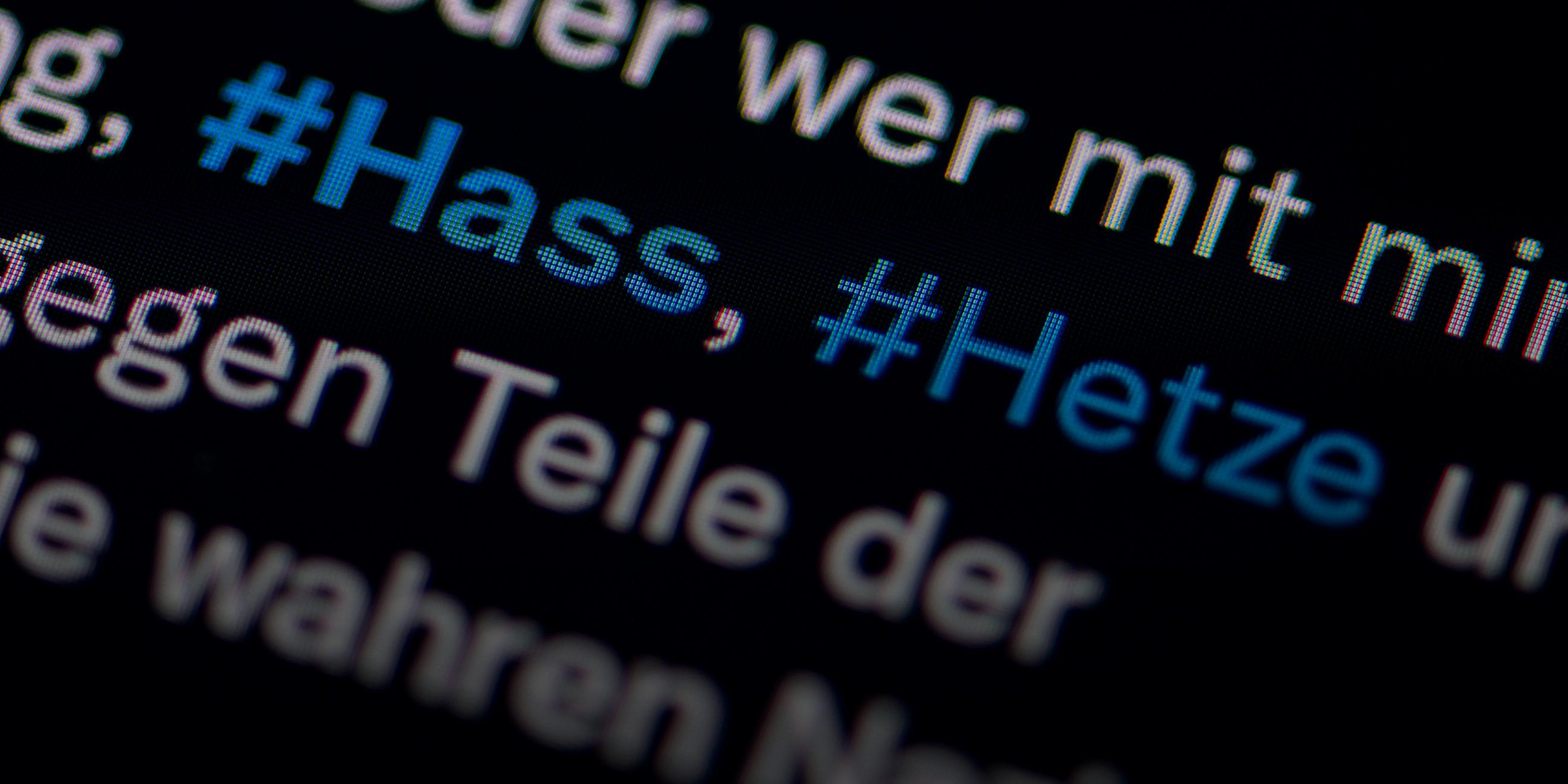 Auf dem Bildschirm eines Smartphones sieht man die Hashtags Hass und Hetze in einem Twitter-Post.