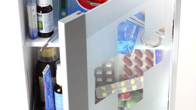 Ein gefüllter Medikamentenschrank mit Glastür als Hausapotheke.