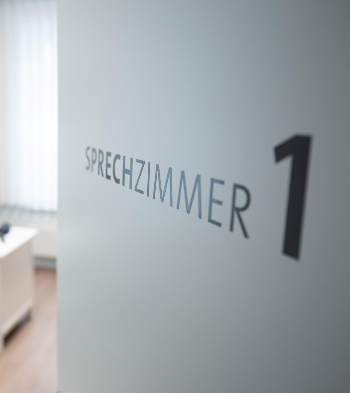 Ein Hausarzt sitzt in einem Sprechzimmer seiner Hausarztpraxis an einem Schreibtisch und arbeitet am Computer.