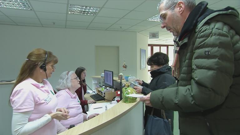 Auf dem Bild sieht man einen Mann der beim Emfang einer Praxis steht.