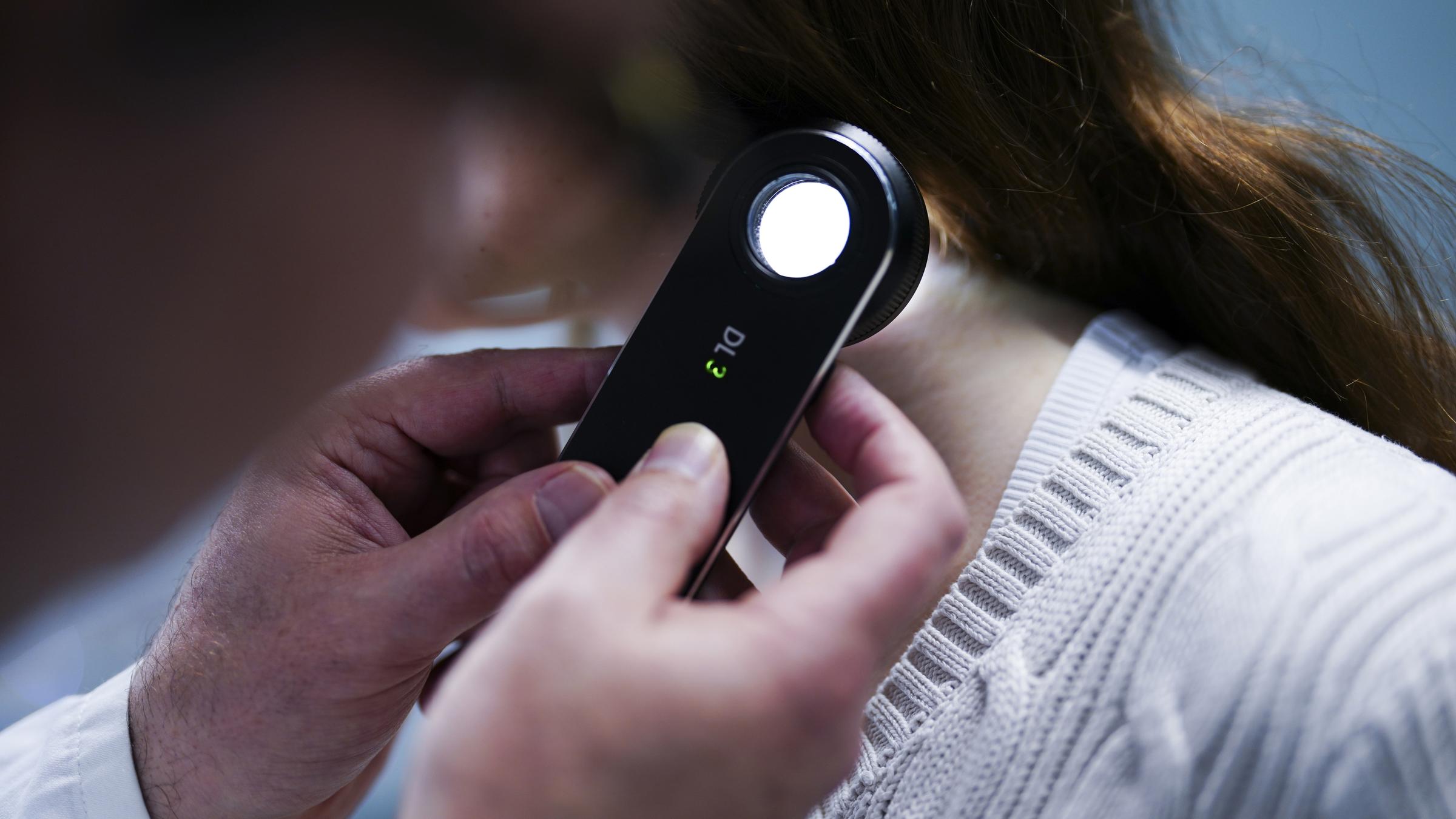 Hautarzt untersucht eine Patientin mit Auflichtmikroskop