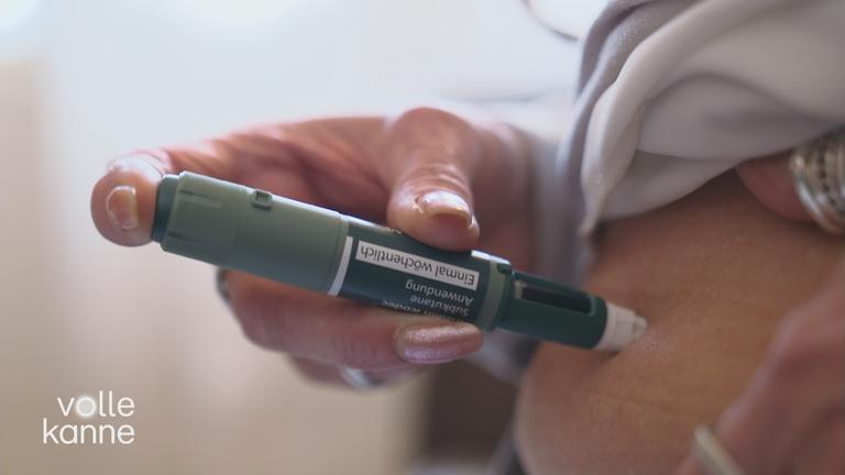 Eine Person spritzt sich mit einem Injektionsstift zur Medikamentengabe in die Bauchregion.