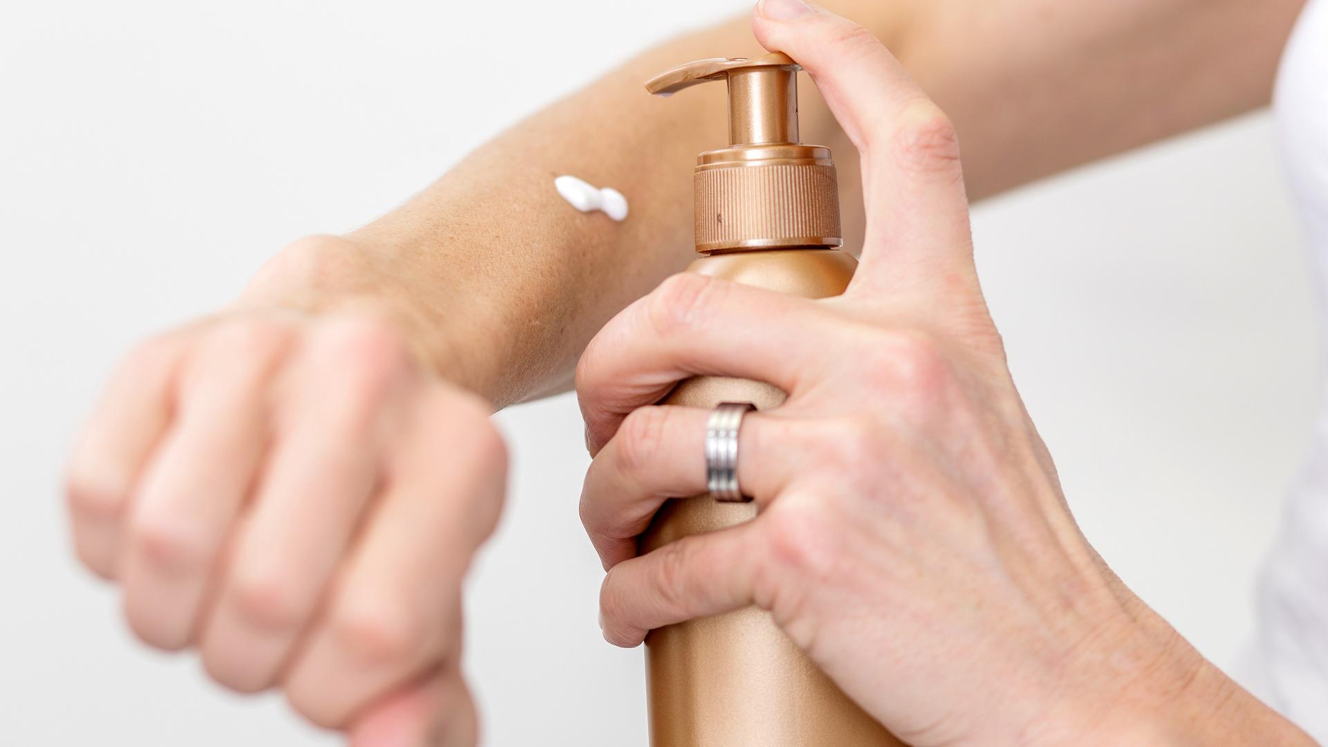 Haupflege im Sommer: Aus einem Spneder wird ein Pflegeprodukt auf einen Arm gesprüht.