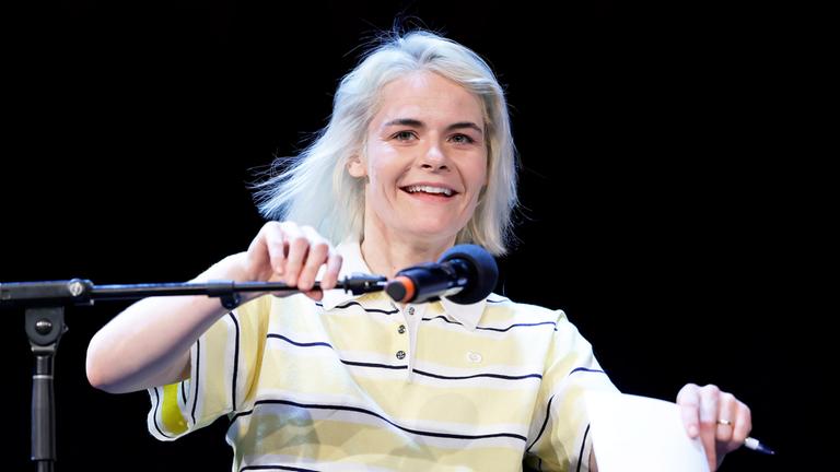 Hazel Brugger ist mit einem Standmikrofon vor ihrem Gesicht zu sehen.