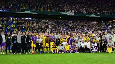 Spieler von Borussia Dortmund und HEBC posen für ein gemeinsames Gruppenfoto vor den Fans des HEBC