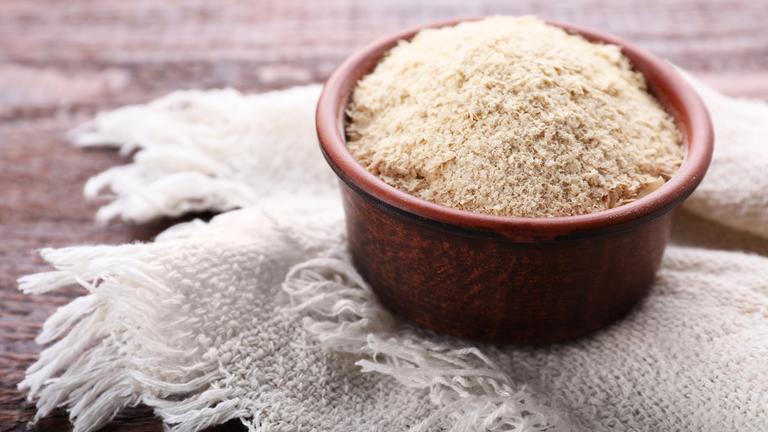 Hefeflocken in einem Tonschälchen auf einer Leinendecke