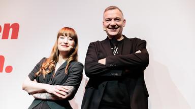 Heidi Reichinnek und Jan van Aken stehen mit verschränkten Armen nebeneinander.