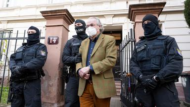 Polizisten führen Heinrich XIII. Prinz Reuß (2.v.r.) nach der Durchsuchung eines Hauses zu einem Polizeifahrzeug