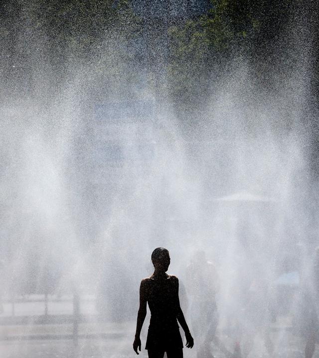 Passanten erfrischen sich an Wasserfontaenen, die von der Stadt Koeln im Rahmen der Hitzeaktion Cooling Cologne auf dem Rudolfplatz ausgelegt wurden.