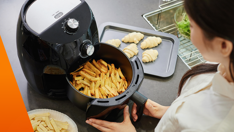 Frau nutzt Heißluftfritteuse und bereitet Pommes zu