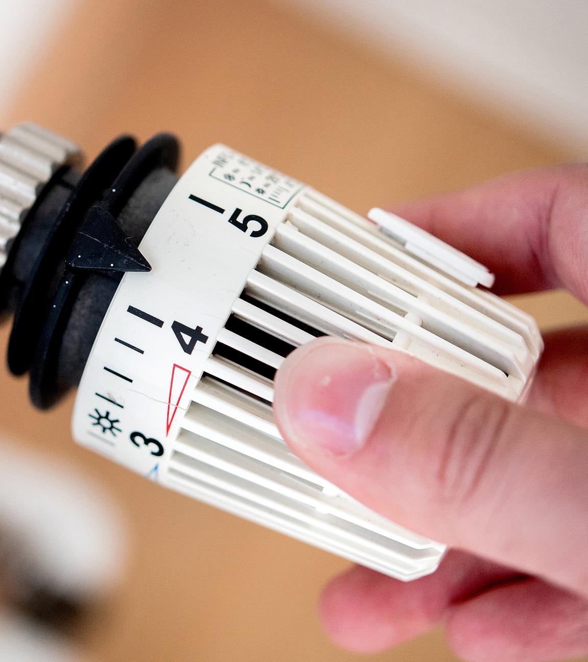 Eine Frau dreht am Thermostat einer Heizung. (Archivbild)