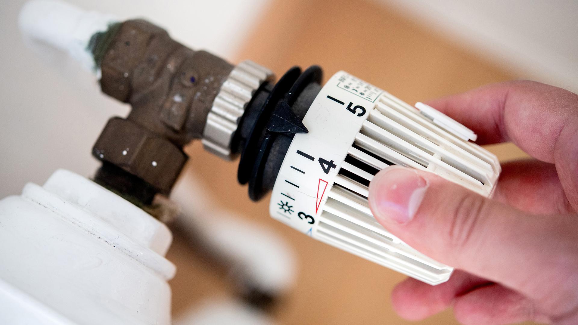 Eine Frau dreht am Thermostat einer Heizung. (Archivbild)