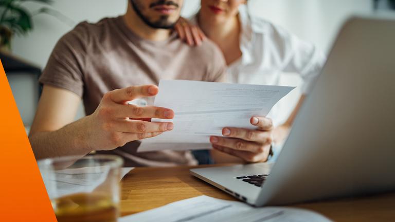 Paar hält Papier in der Hand vor dem Rechner