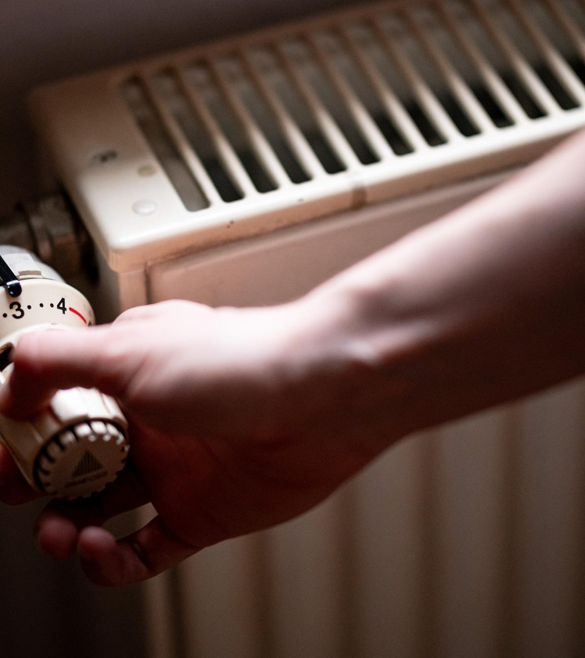 Eine Person benutzt einen alten Heizkörper in einer Berliner Altbauwohnung.