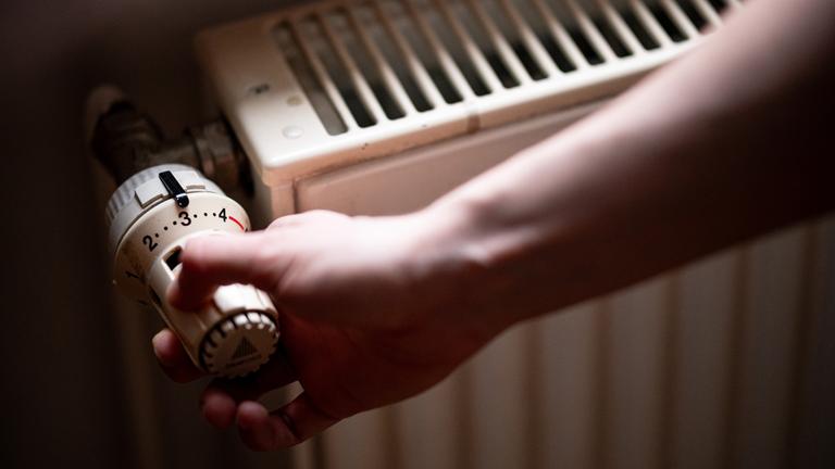 Eine Person benutzt einen alten Heizkörper in einer Berliner Altbauwohnung.