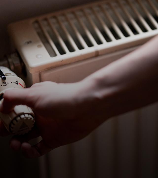 Symbolbild:  Eine Person benutzt einen alten Heizkörper in einer Berliner Altbauwohnung. 