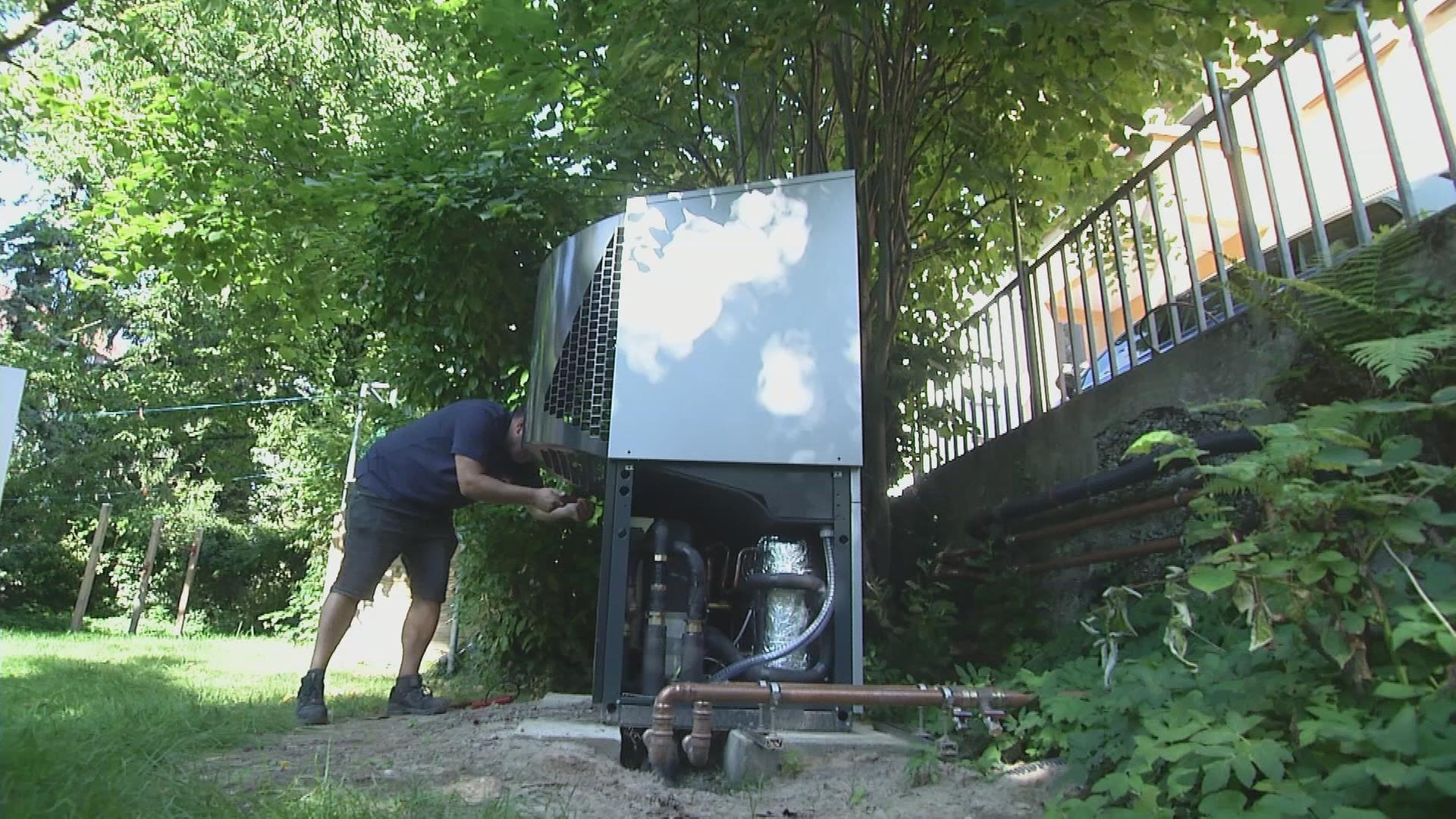 Handwerker baut an Wärmepumpe in Garten