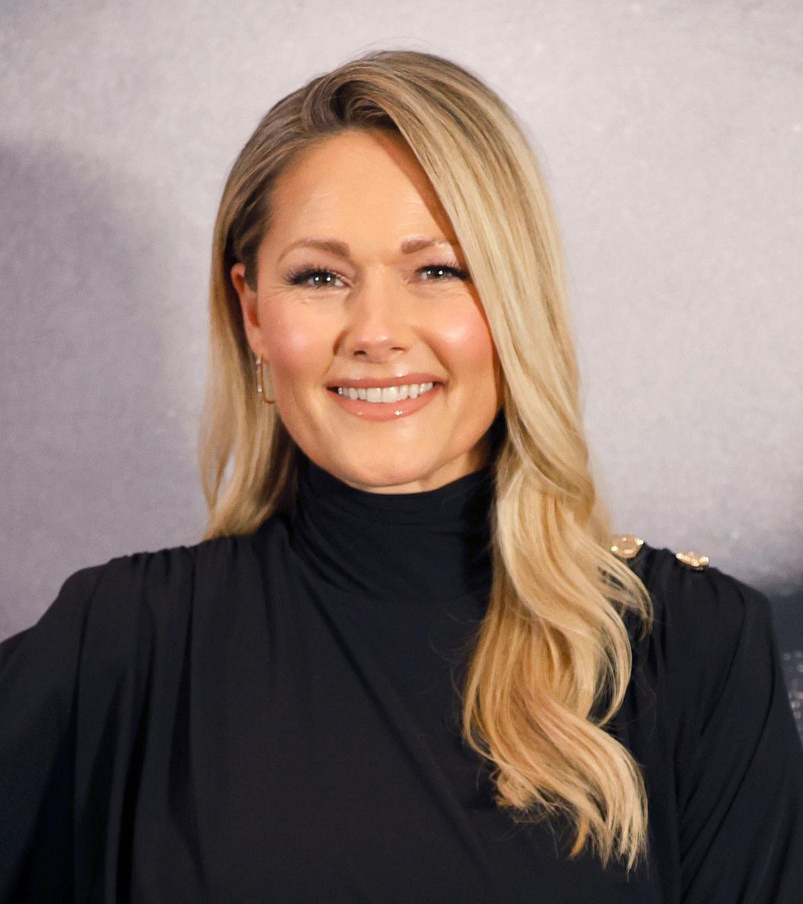 Ein Porträtfoto von Helene Fischer, einer weißen Frau mit blonden, langen Haaren in einem schwarzen, hochgeschlossenen Oberteil.