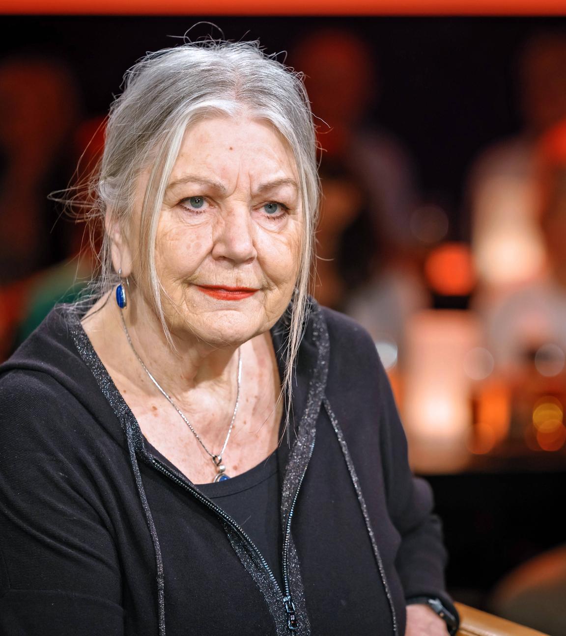 Porträtfoto einer älteren Frau mit zurückgebundenen langen grauen Haaren.