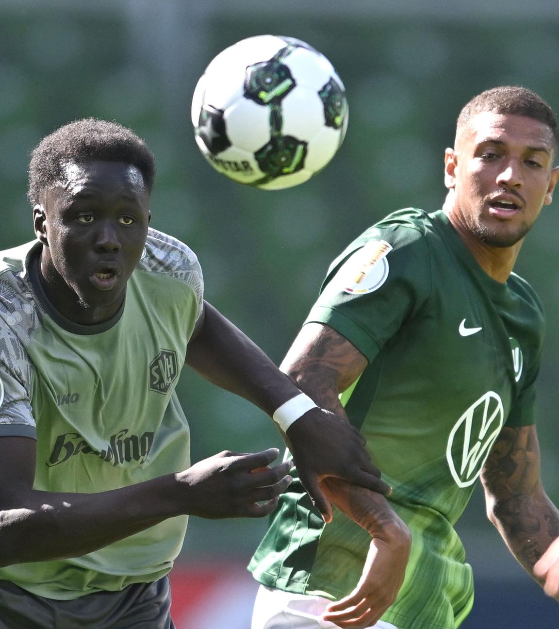 Konstantinos Koulierakis (rechts, VfL Wolfsburg) und Radin Amadou vom SV Hemelingen rennen dem Ball hinterher.
