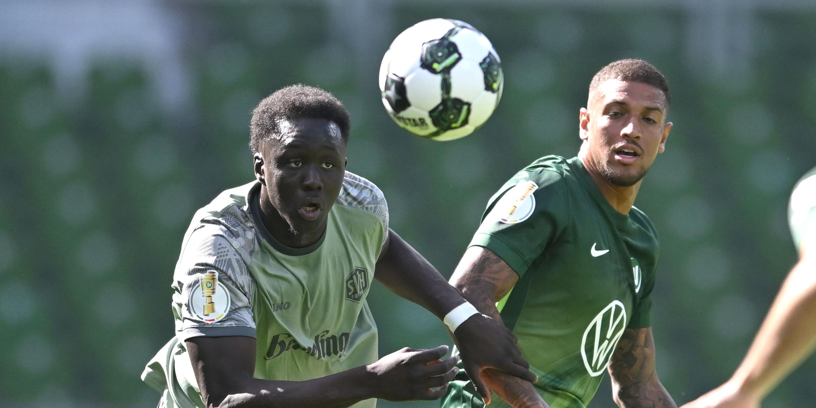 Konstantinos Koulierakis (rechts, VfL Wolfsburg) und Radin Amadou vom SV Hemelingen rennen dem Ball hinterher.