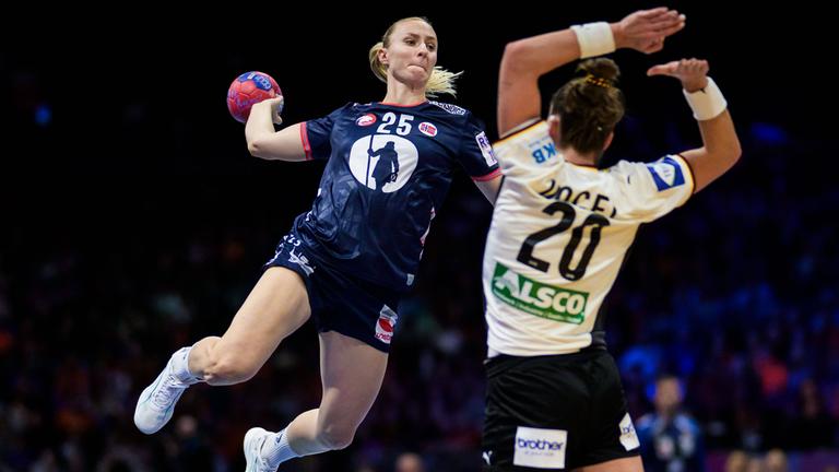 Norwegens Handballnationalspielerin Henny Ella Reistad setzt zum Wurf aus dem Sprung an um den Ball über die deutsche Nationalspielerin Emily Vogel zu werfen