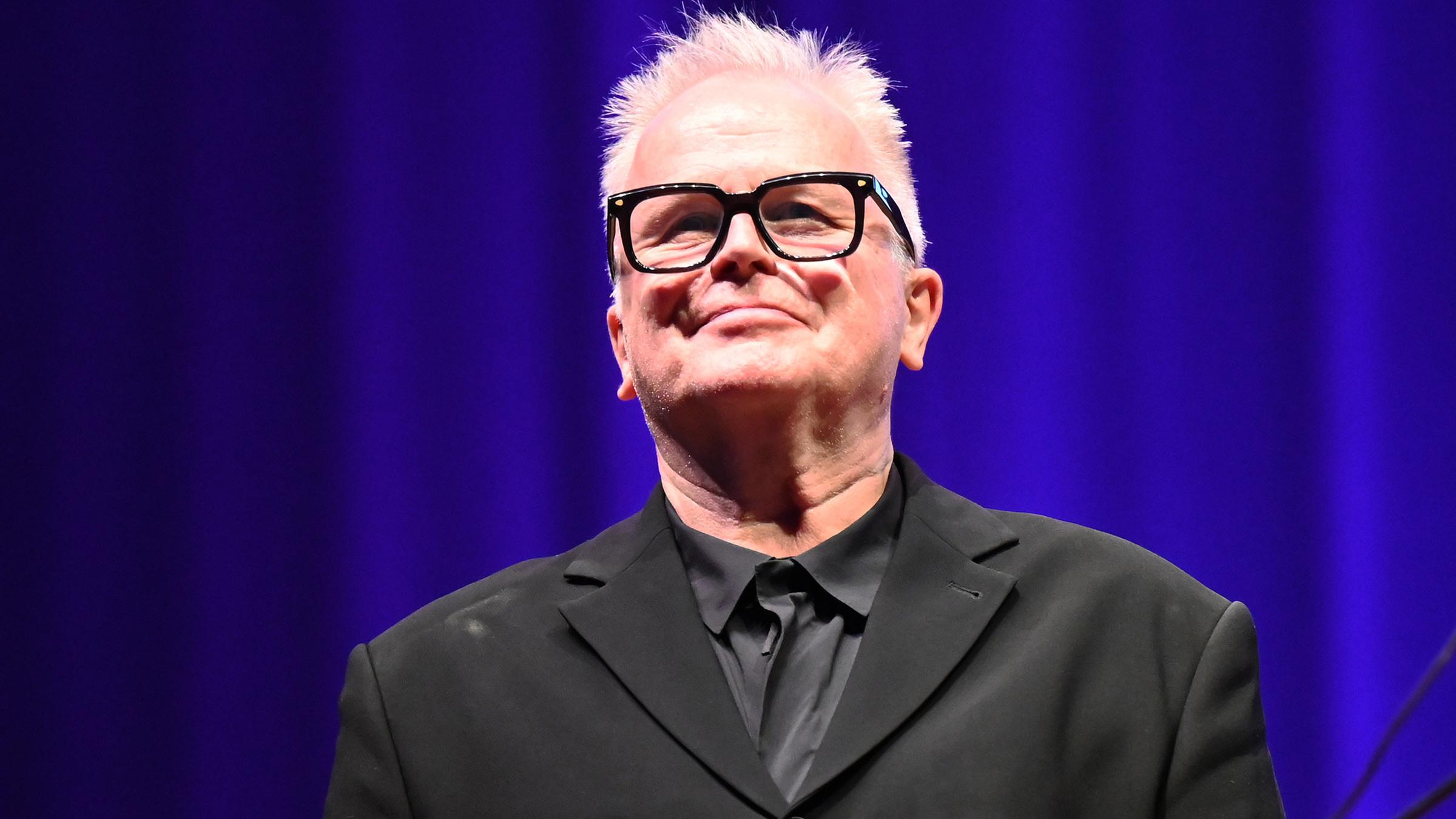 Herbert Grönemeyer vor einem blauen Hintergrund, er lächelt.