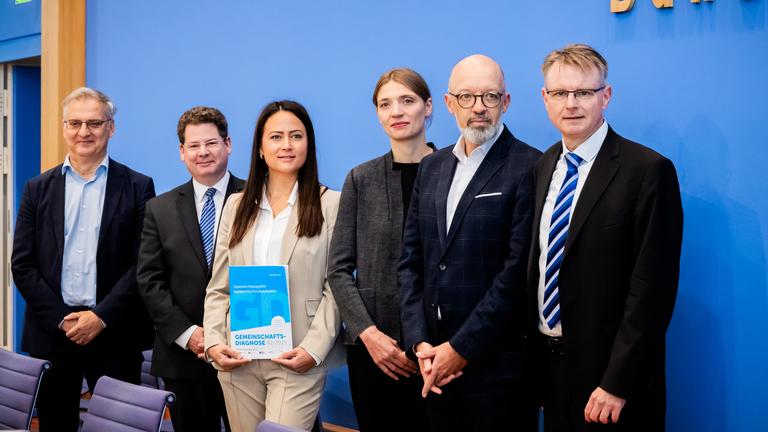 Mehrere Personen mit der Herbstprognose im Saal der Bundespressekonferenz.