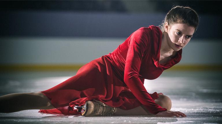Kati Witt (Lavinia Nowak) sitzt nach einem Sturz auf der Eisfläche und stützt sich mit einer Hand ab.