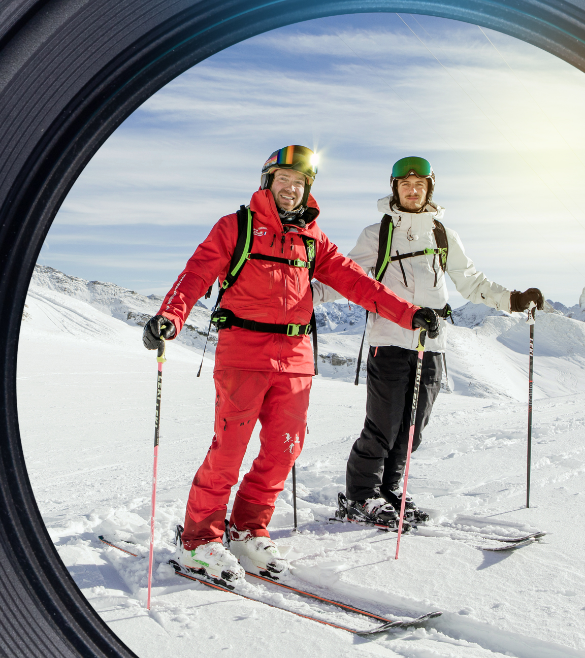 Zwei Männer mit Ski stehen auf dem Berg mitten im Schnee.