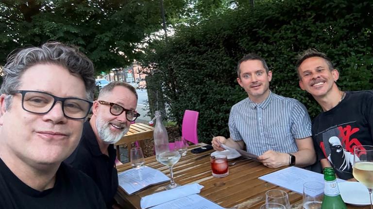 Die Hobbit-Schauspieler Elijah Wood, Sean Astin, Dominic Monaghan und Billy Boyd sitzen an einem Tisch und posieren für ein Foto.