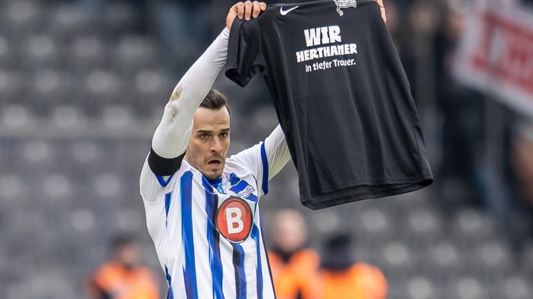 Berlins Haris Tabakovic hält am 21.01.2024 ein schwarzes T-Shirt mit Schriftzug: Wir Herthaner in tiefer Trauer. 