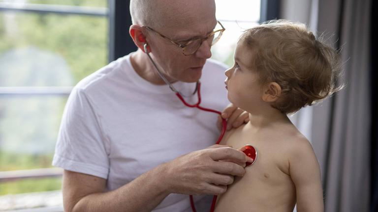 Ein Arzt untersucht ein Kleinkind mit Stethoskop.