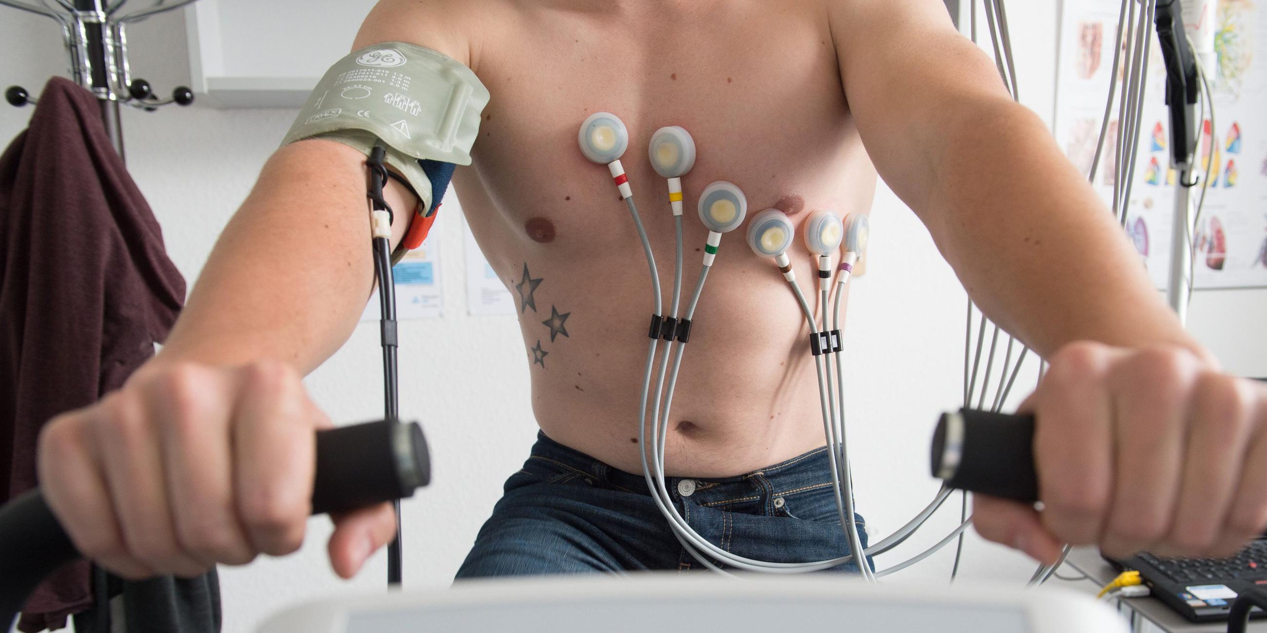 Ein Mann sitzt während eines Belastungs-EKGs auf einem Ergometer. (Symbolfoto)