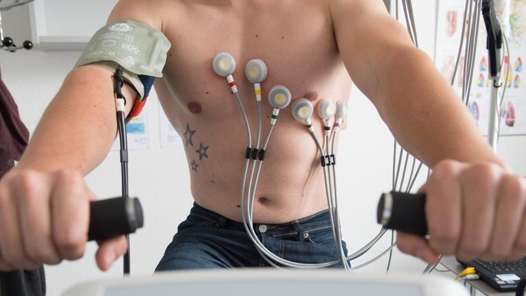 Ein Mann sitzt während eines Belastungs-EKGs auf einem Ergometer. (Symbolfoto)