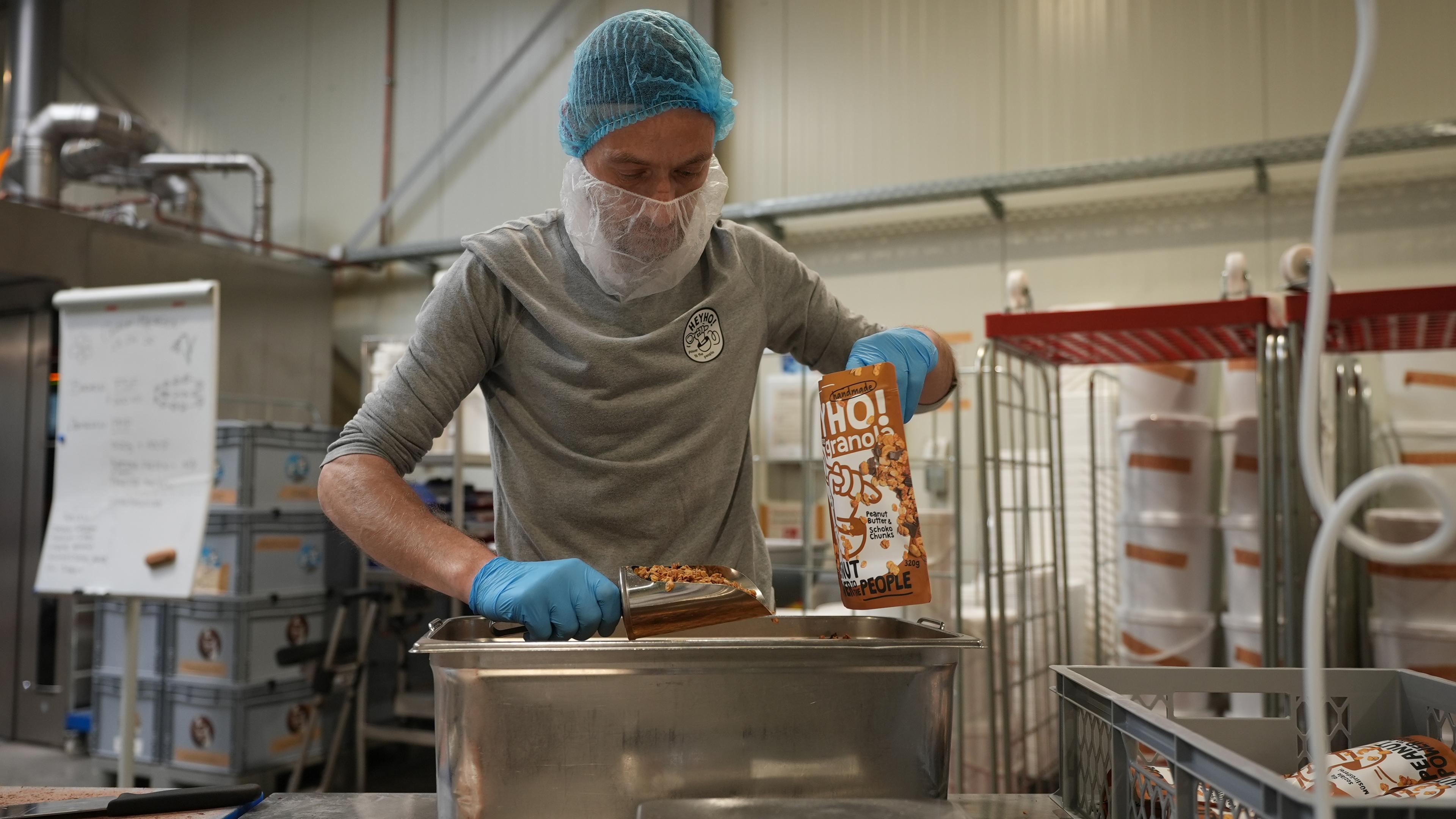 Daniel, Mitarbeiter beim Sozialunternehmen heyho, verpackt Müsli. 