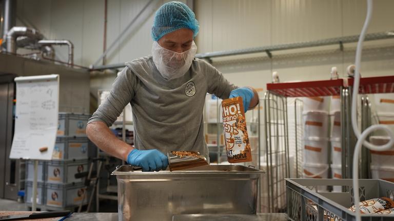 Daniel, Mitarbeiter beim Sozialunternehmen heyho, verpackt Müsli. 