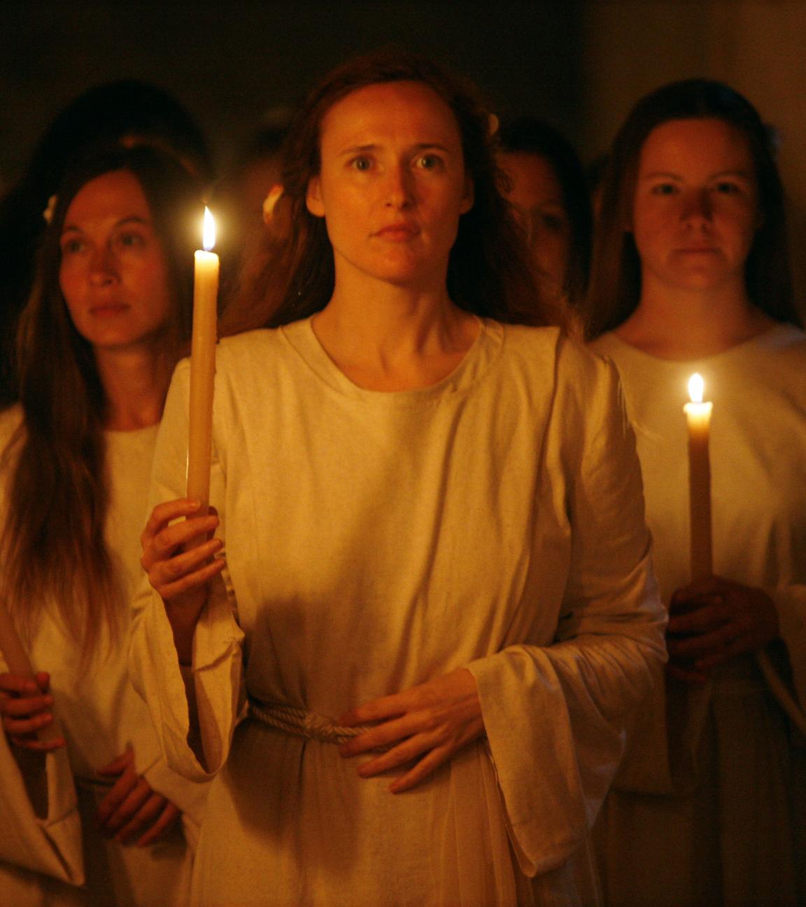 Spielszene: Hildegard von Bingen mit Gefolginnen. Alle trage weiße Gewänder und eine Kerze in der Hand.