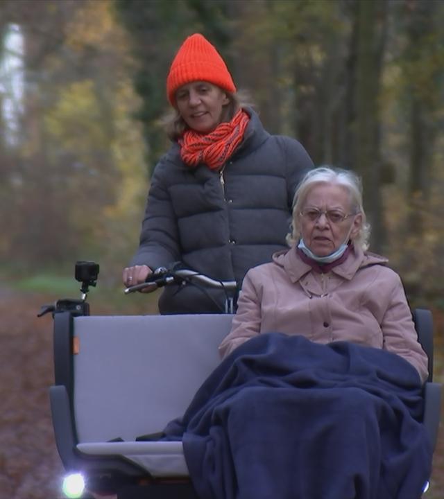 Seniorin wird im Wald spazieren gefahren