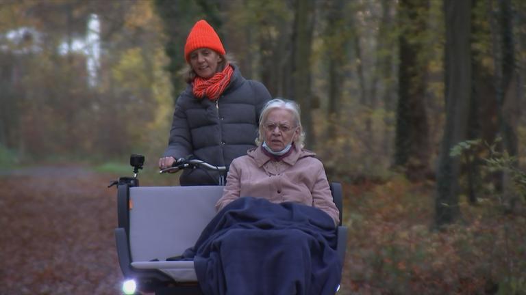 Seniorin wird im Wald spazieren gefahren