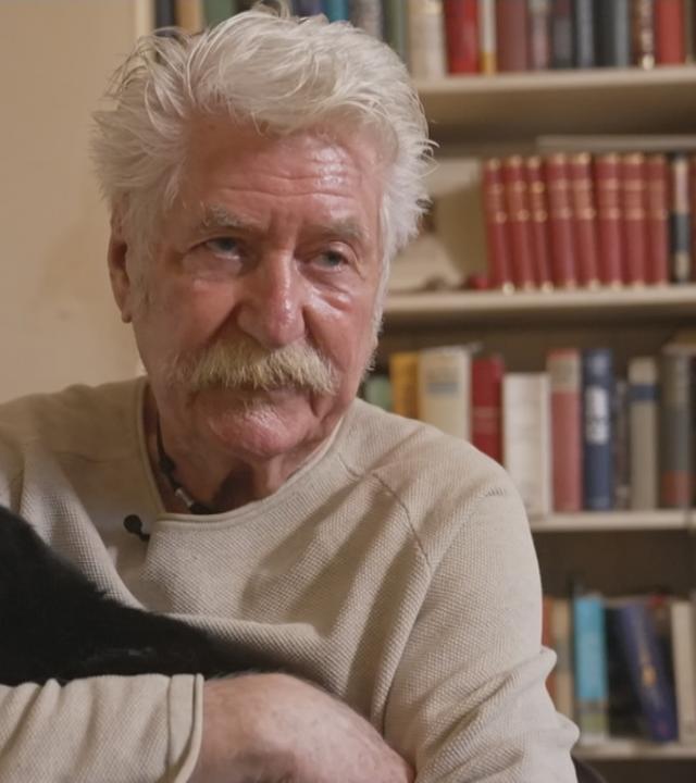 Mann mit seiner schwarzen Katze auf dem Arm 