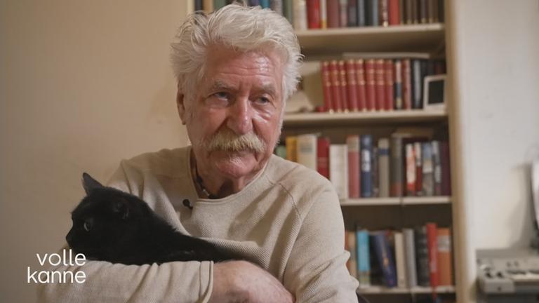 Mann mit seiner schwarzen Katze auf dem Arm 