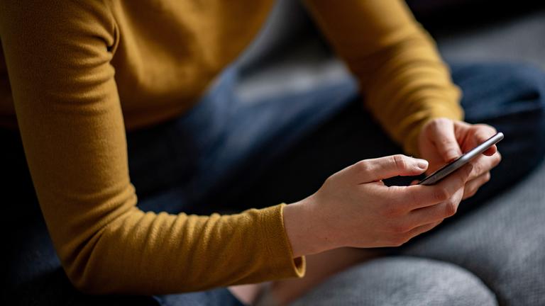 Eine junge Frau hält ein Smartphone in der Hand, aufgenommen am 24.04.2021