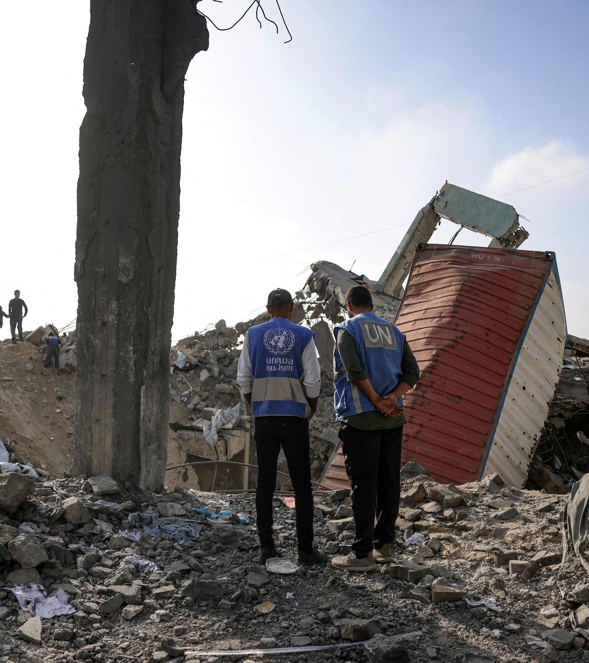 Zwei UN-Hilfskräfte stehen in den Trümmern einer Schule in Gaza.