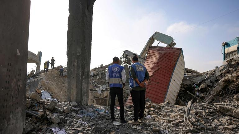 Zwei UN-Hilfskräfte stehen in den Trümmern einer Schule in Gaza.