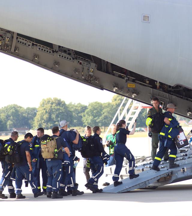 Einsatzkräfte besteigen ein Transportflugzeug auf dem Luftwaffen-Stützpunkt Wunstorf.