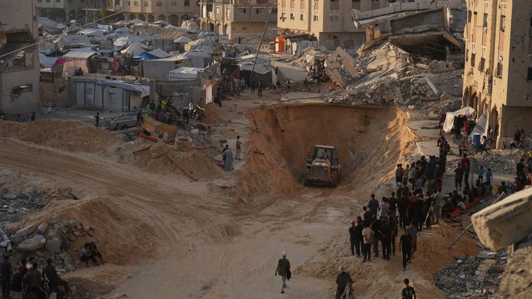 alästinensische Gebiete, Chan Junis: Palästinenser beobachten Mitglieder der militanten Hamas bei der Suche nach Leichen von Geiseln mit schwerem Gerät im Gebiet von Hamad-Stadt im südlichen Gazastreifen.