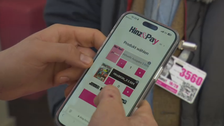 Ein Handy scannt den Ausweis eines Verkäufers der Straßenzeitung Hinz&Kunzt und wählt ein Produkt auf dem Bildschirm aus.